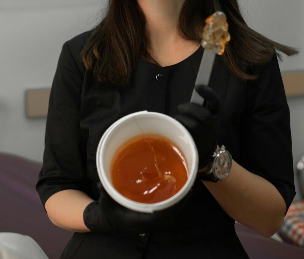 Brunette woman holds honey jar indoors, showcasing food therapy concept.